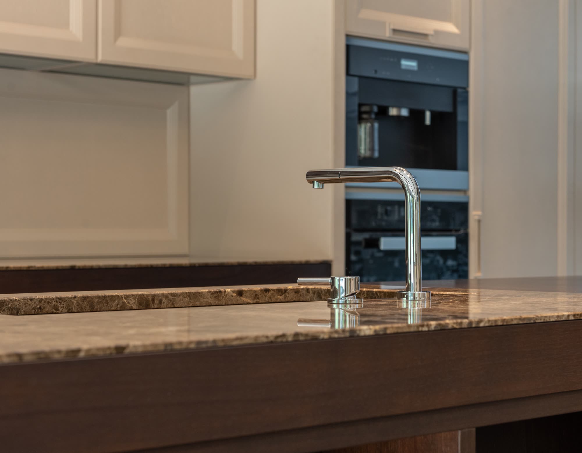 Kitchen with granite countertop, chrome faucet and built-in ovens